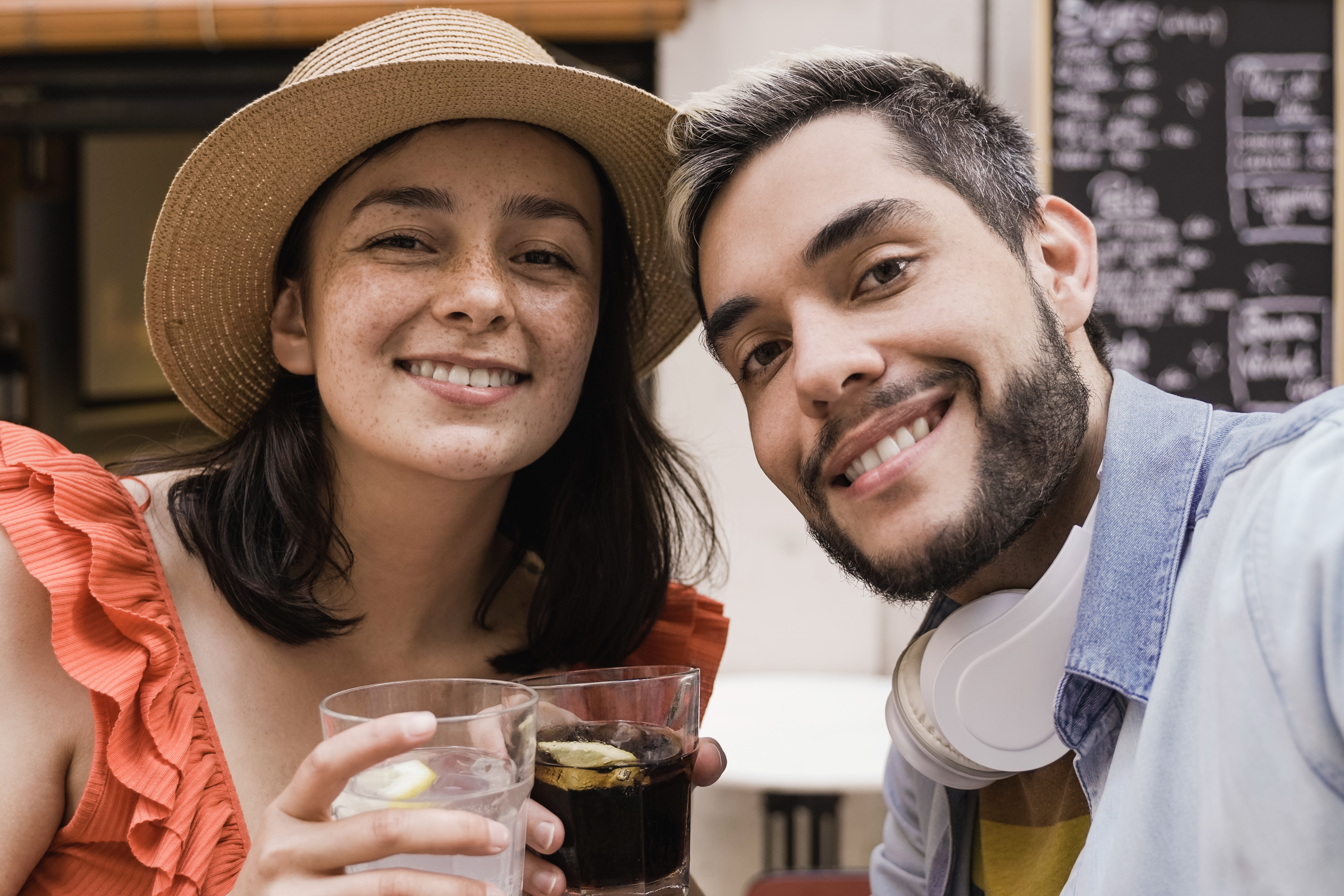 Young happy couple having fun taking selfie outdoor at bar restaurant - Focus on girl face